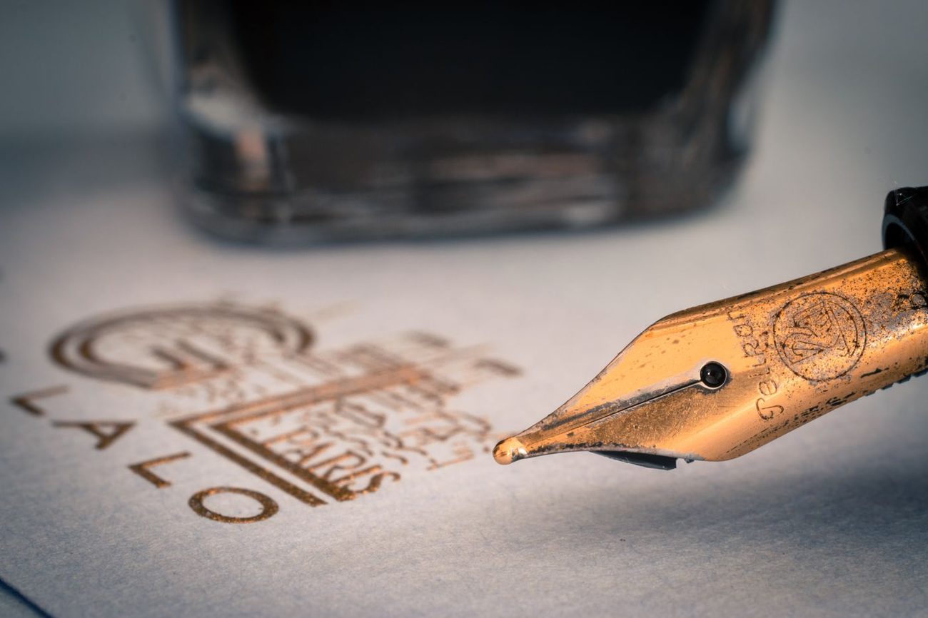 A gold fountain pen nib resting on fine writing paper