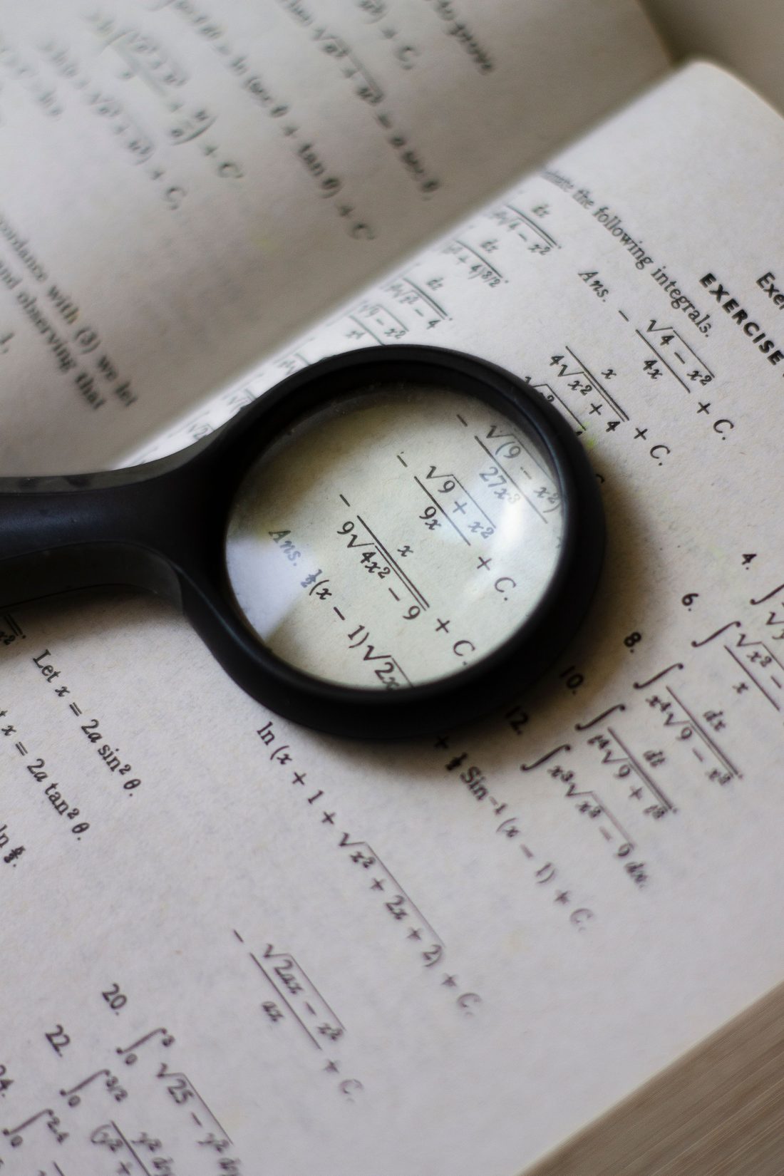 A magnifying glass held over a page of integrals in an old mathematics textbook